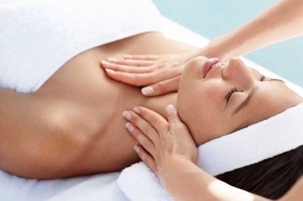 Relaxing spa treatment with a woman receiving a soothing neck massage on a soft white towel.