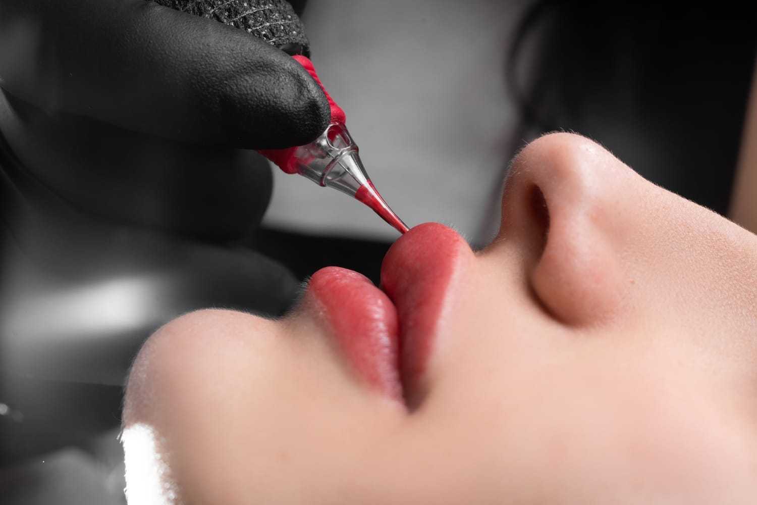 Lip tattooing procedure being performed with a red ink needle.