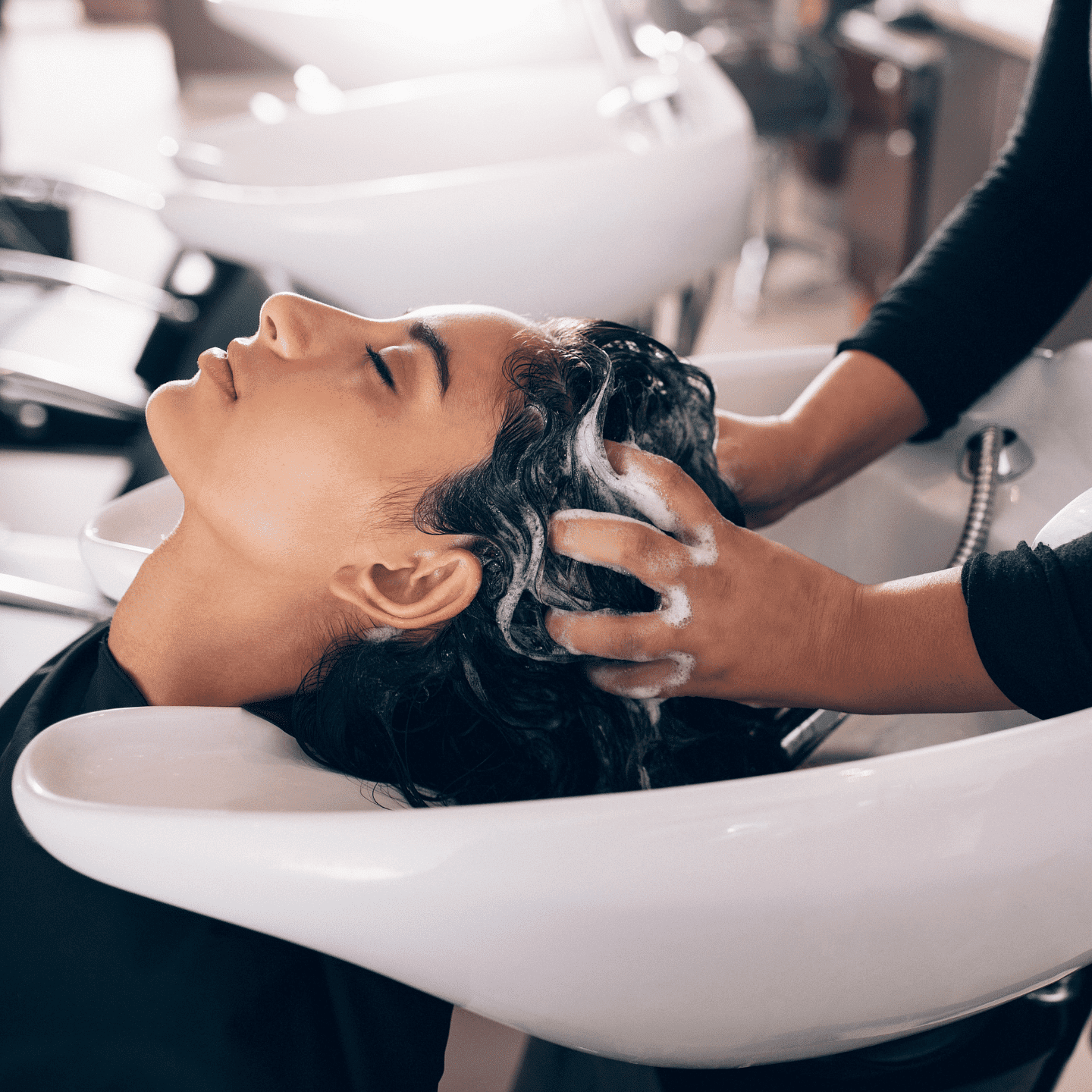 Person getting their hair washed at a salon sink by a stylist.
