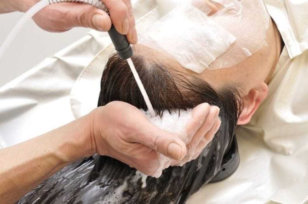 Hair salon treatment with foam and water spray on a client's scalp.