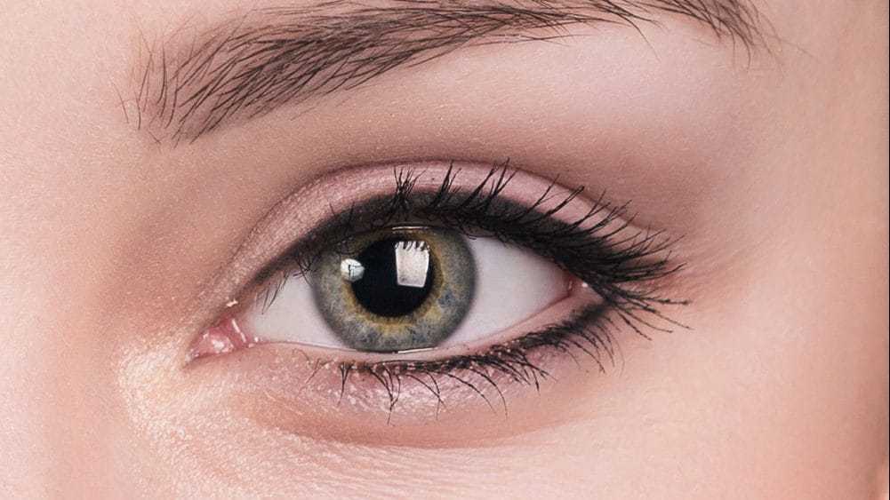 Close-up of a person's eye with green iris and defined eyelashes.